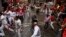 Revelers run around Nunez del Cubillo's fighting bulls on the Estafeta corner during the seventh running of the bulls at the San Fermin Festival, in Pamplona, northern Spain, Wednesday, July 13, 2016.