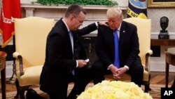 President Donald Trump prays with American Pastor Andrew Brunson in the Oval Office of the White House, Oct. 13, 2018, in Washington. Brunson returned to the U.S. after he was freed Friday, having been detained for nearly two years in Turkey.