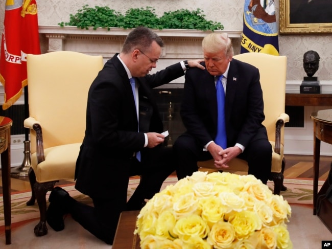 President Donald Trump prays with American Pastor Andrew Brunson in the Oval Office of the White House, Oct. 13, 2018, in Washington. Brunson returned to the U.S. after he was freed Friday, having been detained for nearly two years in Turkey.