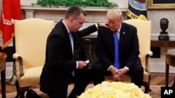 President Donald Trump prays with American Pastor Andrew Brunson in the Oval Office of the White House, Oct. 13, 2018, in Washington. Brunson returned to the U.S. after he was freed Friday, having been detained for nearly two years in Turkey.