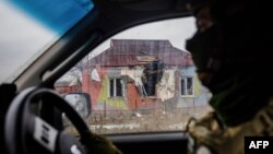 A Ukrainian serviceman drives a car past a damaged house following shelling in eastern Ukraine's Donetsk region, on Oct. 30, 2022.