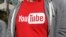 FILE - A YouTube logo on a t-shirt is worn by a person near a YouTube office building in San Bruno, California, April 4, 2018. The video streaming company has announced it will allow more medical sources to share videos on its platform.