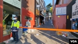 A Seoul police officer stands near a cordoned-off alley in the Itaewon district, Oct. 31, 2022, where at least 154 people died in a crowd surge on Saturday. (William Gallo/VOA.)