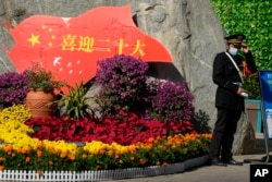 一名保安站在北京街头一处庆祝中共二十大的花坛旁。（2022年10月9日）