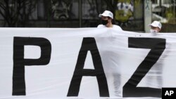 ARCHIVO - Excombatientes de las FARC y activistas sociales participan en una marcha para exigir al gobierno que garantice su derecho a la vida y el cumplimiento del acuerdo de paz de 2016, en Bogotá, Colombia, en noviembre de 2020.