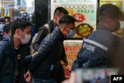 FILE - Stand News chief editor Patrick Lam, center, is brought to the news outlet's office building in handcuffs after police were deployed to search the premises in Hong Kong's Kwun Tong district on Dec. 29, 2021.