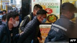 ARCHIVO - El editor jefe de Stand News, Patrick Lam (centro), es llevado esposado al edificio del medio de comunicación después de que la policía fuera desplegada para registrar las instalaciones en el distrito Kwun Tong de Hong Kong el 29 de diciembre de 2021.