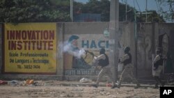 Un oficial de policía lanza gas lacrimógeno a los manifestantes durante una protesta para rechazar una fuerza militar internacional solicitada por el gobierno y exigir la renuncia del primer ministro Ariel Henry, en Puerto Príncipe, Haití, el 17 de octubre de 2022.