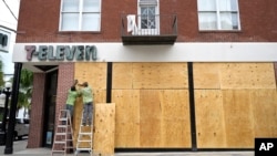 Workers board up the windows of a 7-Eleven convenience store in preparation for Hurricane Ian, Sept. 27, 2022, in Tampa, Fla.