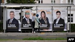 People walk past electoral posters in Sarajevo on Oct. 1, 2022, on the eve of general elections in Bosnia.