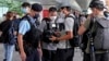 FILE - Police officers stop and check journalists near the Convention and Exhibition Center ahead of a ceremony to be held at the venue, in Hong Kong, July 1, 2022.