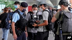 FILE - Police officers stop and check journalists near the Convention and Exhibition Center ahead of a ceremony to be held at the venue, in Hong Kong, July 1, 2022.