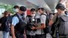 FILE -Police officers stop and check journalists near the Convention and Exhibition Center, where Chinese President Xi Jinping will attend a ceremony in Hong Kong, July 1, 2022.