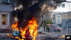 A medical worker runs past a burning car after a Russian attack in Kyiv, Ukraine, Oct. 10, 2022.