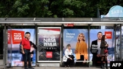 People wait at a bus station decorated with electoral posters in Sarajevo, Oct. 1, 2022, on the eve of general elections in Bosnia.