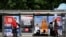 People wait at a bus station decorated with electoral posters in Sarajevo, Oct. 1, 2022, on the eve of general elections in Bosnia.