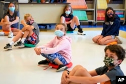 FILE - Fifth graders wearing face masks sit while social-distancing during a music class at Milton Elementary School in Rye, New York, May 18, 2021.