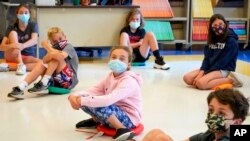 FILE - Fifth graders wear face masks sit while social-distancing during a music class at Milton Elementary School in Rye, New York, May 18, 2021.