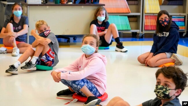 FILE - Fifth graders wear face masks sit while social-distancing during a music class at Milton Elementary School in Rye, New York, May 18, 2021.