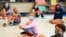 FILE - Fifth graders wearing face masks sit while social-distancing during a music class at Milton Elementary School in Rye, New York, May 18, 2021.