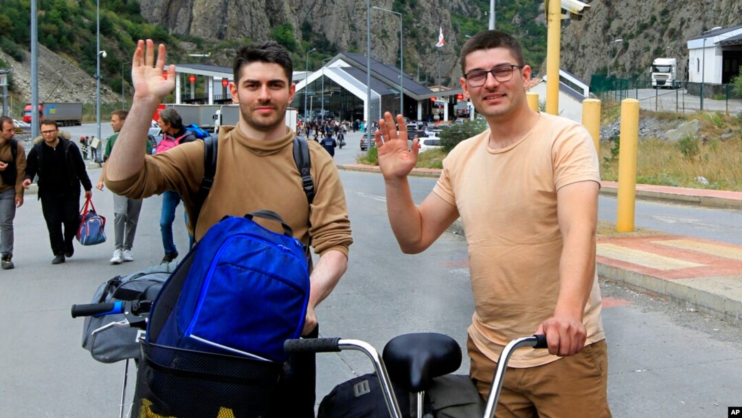 ARHIVA - Dvojica Rusa mašu fotografu pošto su prešla granični prelaz iz Rusije u Gruziju, 28. septembra 2022.