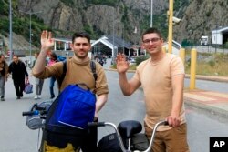 Dvojica Rusa mašu fotografu nakon što su prešla granični prelaz iz Rusije u Gruziju, 28. septembra 2022.