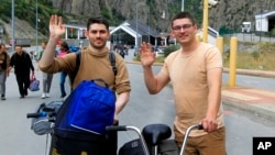 FILE - Two Russians wave to a photographer after they crossed the border between Georgia and Russia at Verkhny Lars in Georgia, Sept. 28, 2022.