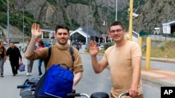 FILE - Two Russians wave toward a photographer after they crossed the border between Georgia and Russia at Verkhny Lars in Georgia, Sept. 28, 2022. 