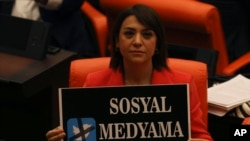 A lawmaker from the main opposition Republican People's Party holds up a placard that reads "Don't touch my social media" in protest at the parliament, in Ankara, Turkey, Oct. 11, 2022.