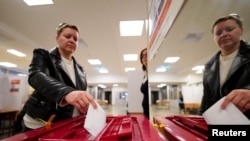 Seorang perempuan sedang memasukkan surat suara dalam pemilu di Kota Riga, Latvia, Sabtu, 1 Oktober 2022. (Foto: Janis Laizans/Reuters)