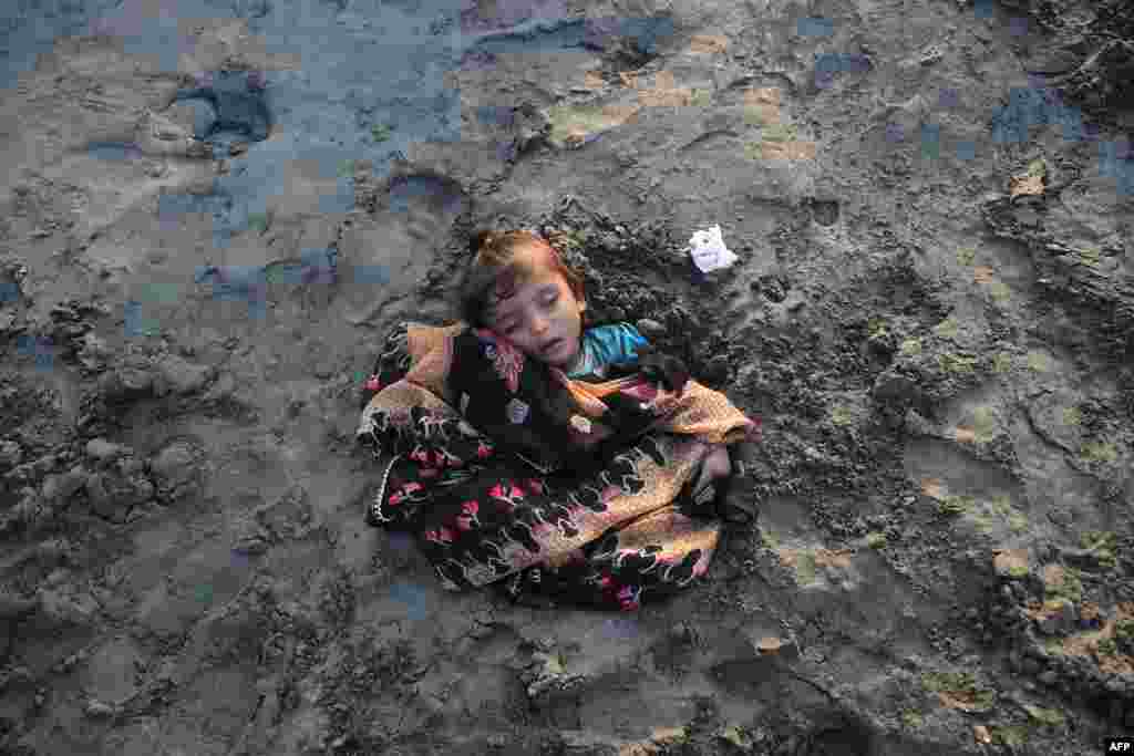 A girl sleeps while seen covered in sand in a beach by her parents with the believe that exposure during a solar eclipse will heal her illness, in Karachi, Pakistan, Oct. 25, 2022.