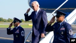 President Joe Biden returns a salute as he exits Air Force One at Philadelphia International Airport in Philadelphia, Oct. 7, 2022. 