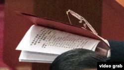 视频截图显示，习近平叫来的工作人员手里拿着那份不许胡锦涛在中共20大会场翻阅的人事名单。