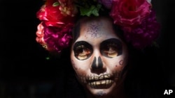 A woman dressed as Mexico's iconic "Catrina" poses for tourists in Mexico City's main square, the Zocalo, as part of the Day of the Dead festivities in Mexico City, Oct. 28, 2022.