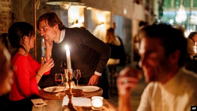 A couple speak as they enjoy a drink and candle lit dinner at Brasserie Surrealiste in Brussels, Sept. 28, 2022.