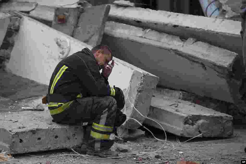 A rescue worker takes a pause as he sits on the debris at the scene where a woman was found dead after a Russian attack that heavily damaged a school in Mykolaivka, Ukraine.