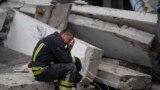 A rescue worker takes a pause as he sits on the debris at the scene where a woman was found dead after a Russian attack that heavily damaged a school in Mykolaivka, Ukraine.