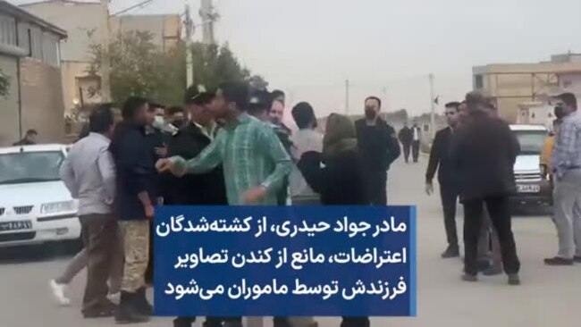 مادر جواد حیدری، از کشته‌شدگان اعتراضات، مانع از کندن تصاویر فرزندش توسط ماموران می‌شود 