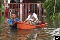Thai resident wade through floodwaters, Thursday, Sept. 29, 2022, in Ubon Ratchathani province, northeastern Thailand.
