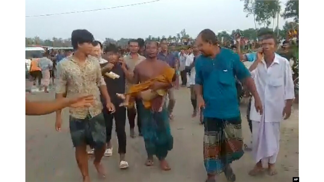 Dalam gambar yang dibuat dari video ini, seorang pria membawa jenazah korban di Panchagarh, Bangladesh, Minggu, 25 September 2022. Sebuah perahu yang membawa sekitar 100 peziarah Hindu terbalik pada Minggu di sebuah sungai di Bangladesh utara, kata polisi. (AP)