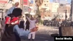 This screen grab from a UGC video posted on Oct. 28, 2022, purports to show demonstrators gesturing and throwing objects as they confront security forces during a protest in the southeastern Iranian city of Zahedan.