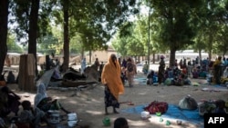 FILE - This photo taken on December 8, 2016, shows a group of people waiting to be integrated into the Internally Displaced People (IDP) camp, in Bama, upon their arrival. 