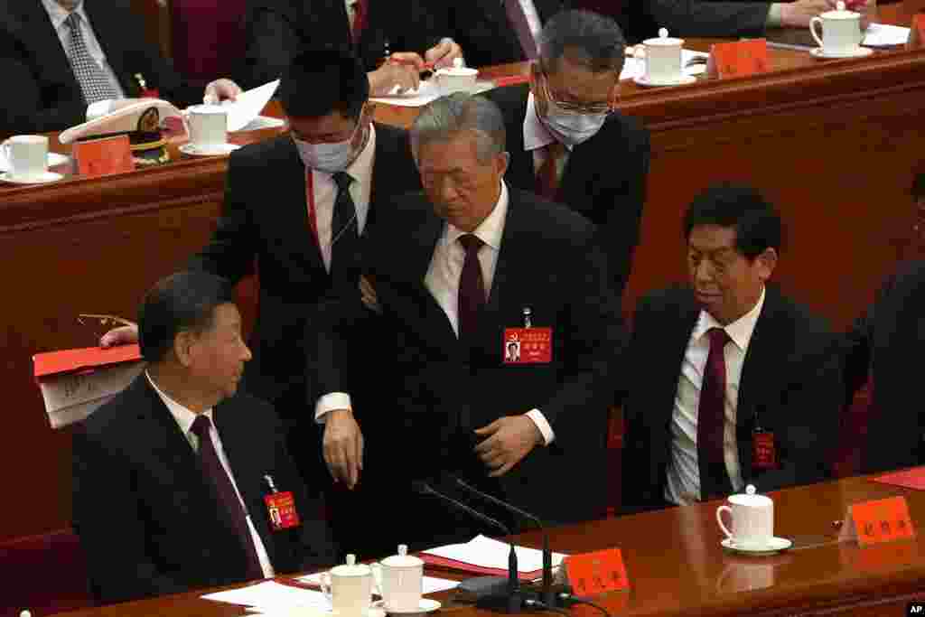 O antigo Presidente chinês Hu Jintao, centro, é acompanhado durante a cerimónia de encerramento do 20&ordm; Congresso Nacional do Partido Comunista governante da China, no Grande Salão do Povo em Pequim, a 22 de Outubro de 2022.