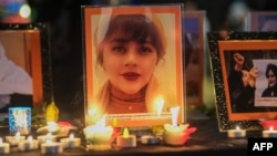 FILE - Candles and pictures of Mahsa Amini are shown during a vigil in Los Angeles for Mahsa Amini, who died in custody of Iran's morality police, Sept. 29, 2022. 
