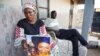 Mariama Kuyateh brandit une photo de son défunt fils Musa, décédé d'une insuffisance rénale aiguë, à Banjul le 10 octobre 2022, après avoir pris le sirop contre la toux fabriqués de la société Indian Pharma Maiden Pharmaceuticals (Photo de MILAN BERCKMANS / AFP)