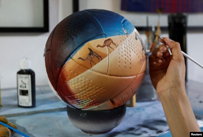 Paraguayan artist Lili Cantero, 29, paints a soccer ball ahead of the 2022 FIFA World Cup, in San Lorenzo, Paraguay October 15, 2022. REUTERS/Cesar Olmedo