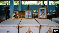 Portraits of young victims of a mass shooting in a nursery are displayed atop their coffins as funeral preparations get underway at Wat Si Uthai temple in Thailand's northeastern Nong Bua Lam Phu province.