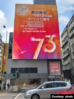 香港街頭懸掛的慶祝中華人民共和國成立73週年的巨幅廣告。美國之音高鋒攝。