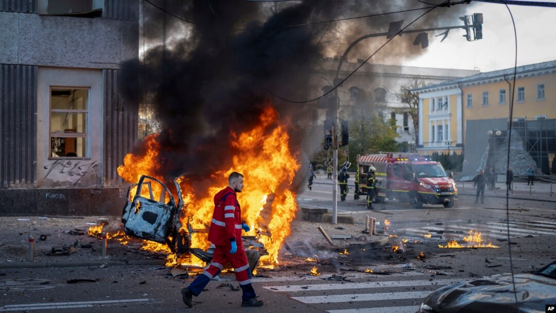 An emergency medical technician walks past a burning car after a Russian missile strike in Kyiv, Ukraine, Oct. 10, 2022. 