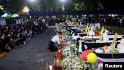FILE - A person pays tribute at the caskets of victims, on the day of a cremation at Wat Rat Samakee temple, following a mass shooting at a child care center, in the town of Uthai Sawan, in the province of Nong Bua Lam Phu, Thailand, Oct. 11, 2022.